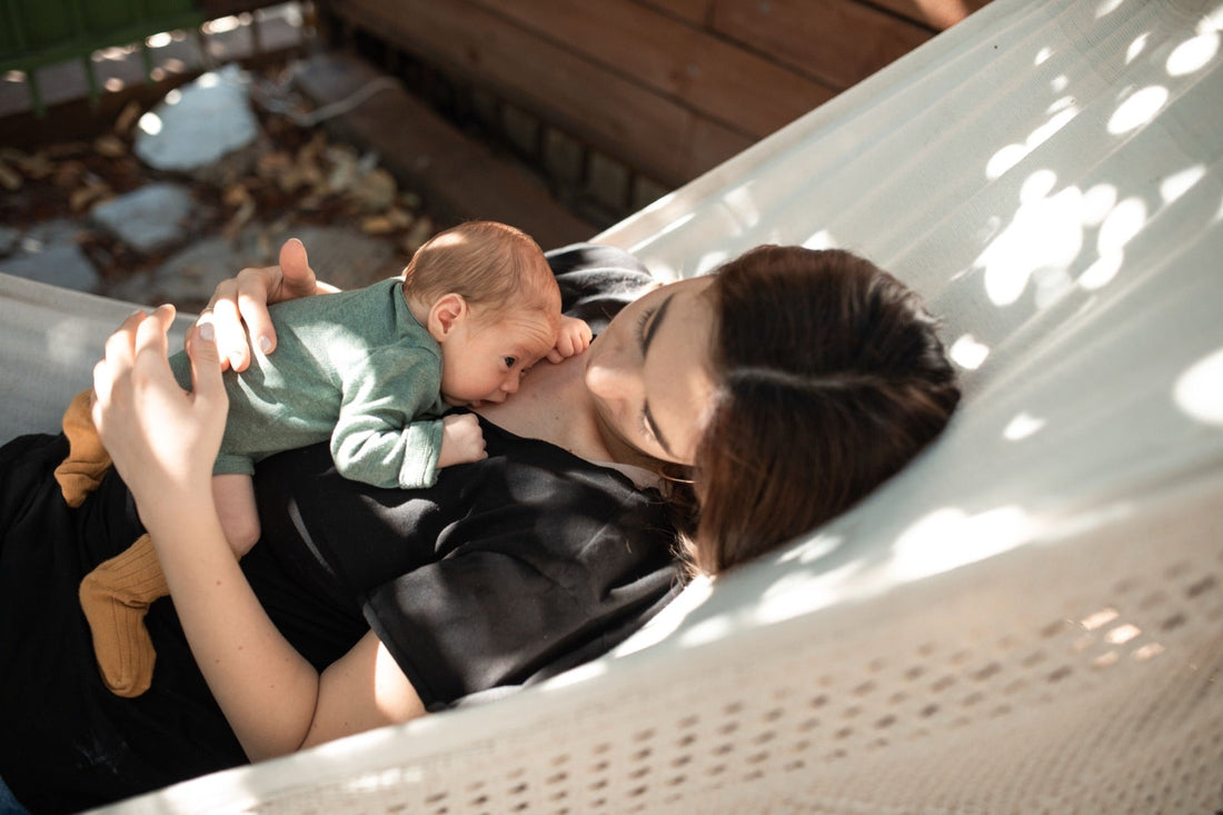 A mother lying in a hammock with her baby